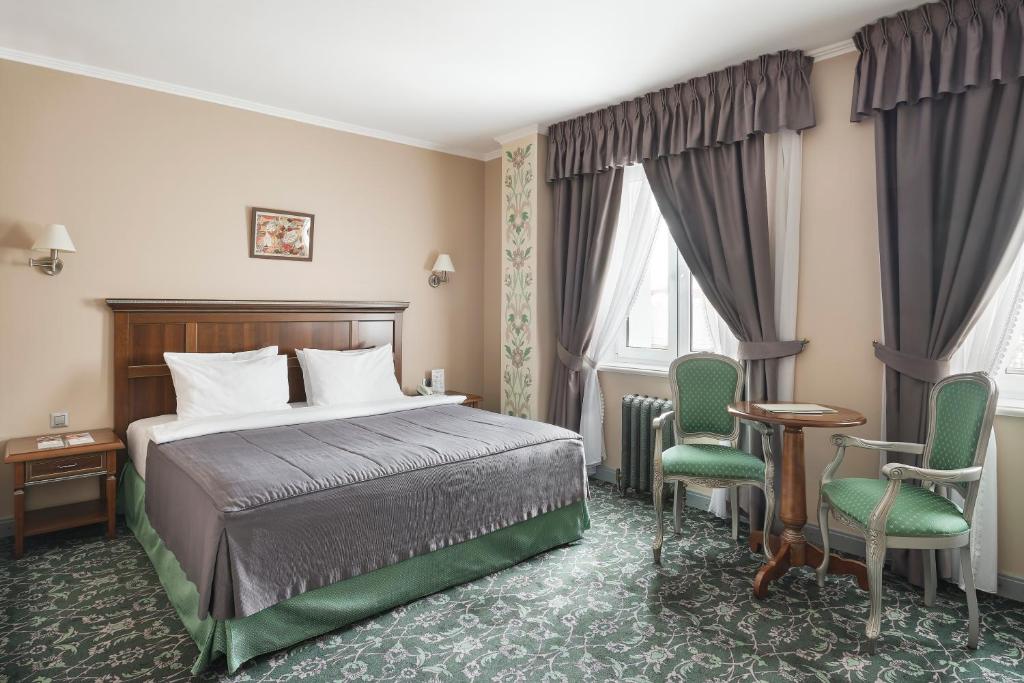 a hotel room with a bed and two chairs at Remezov Hotel in Tyumen