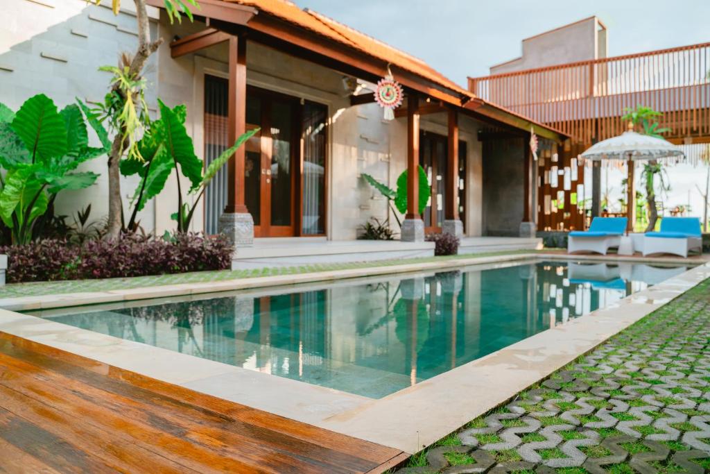 a villa with a swimming pool in front of a house at The Ume in Canggu