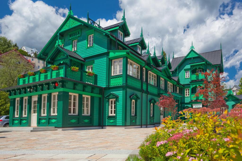 duży zielony dom z białymi oknami w obiekcie WISŁA Cechini w mieście Krynica Zdrój