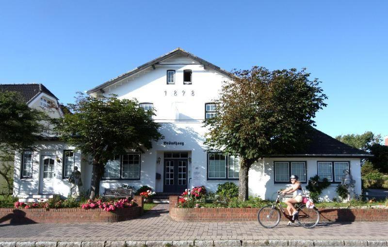 ヴェニングシュテットにあるHaus Brönshoog, Appartement 11 in strandnaher Lageの白い建物前の自転車に乗る男
