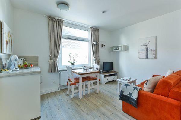 - un salon avec un canapé orange et une table dans l'établissement App-7-in-strandnaher-Lage-Baederstil-Villa-in-Wenningstedt-Sylt, à Wenningstedt
