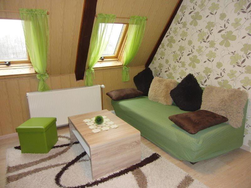 uma sala de estar com um sofá verde e uma mesa em Ferienwohnung-Ritscher-in-Lichtenhain-1 em Lichtenhain