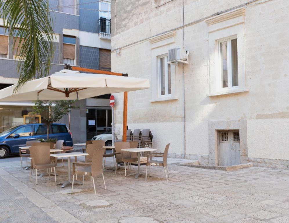 a patio with tables and chairs and an umbrella at Domina Living Apartments - Montecucco in Bisceglie