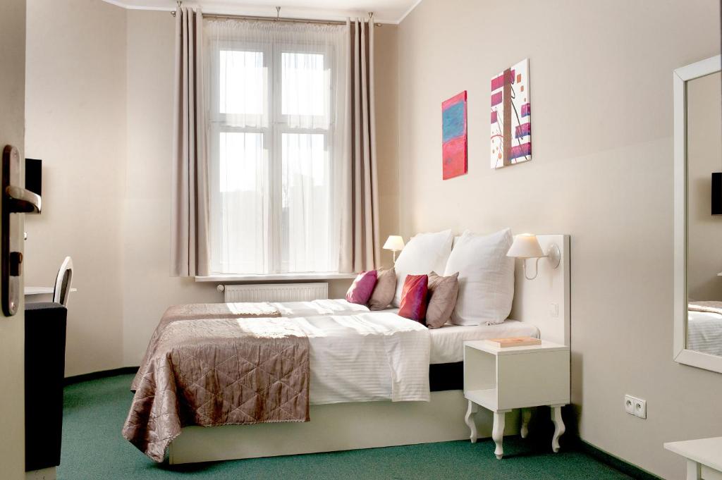 Dormitorio blanco con cama y ventana en Leone Aparthotel en Cracovia