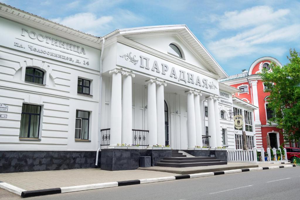 a large white building with columns on a street at Parade Hotel Yaroslavl in Yaroslavl