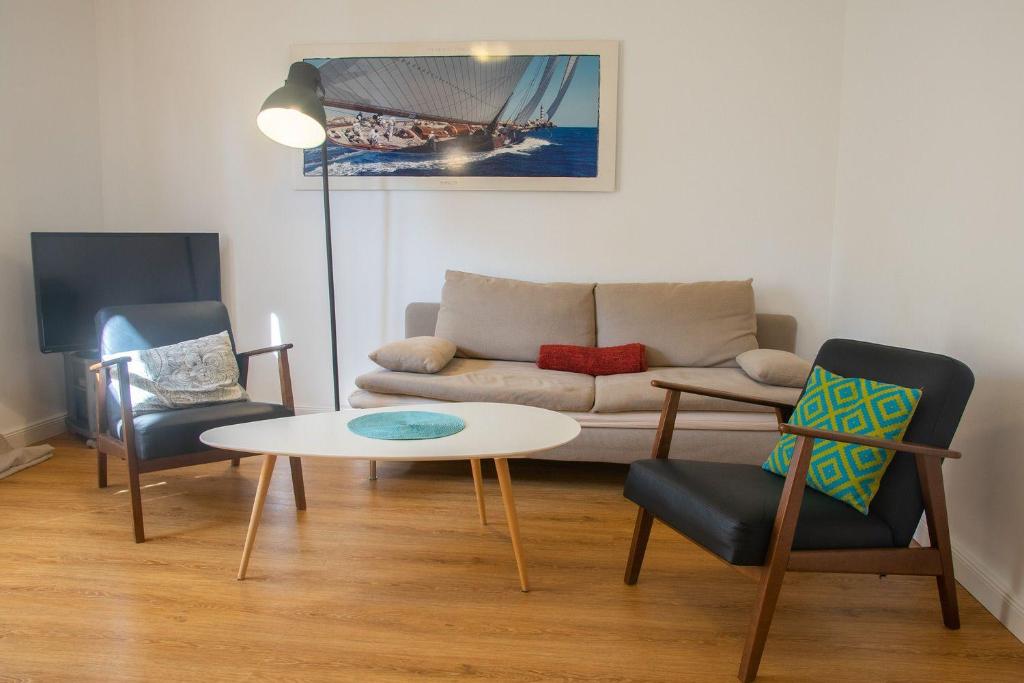 ein Wohnzimmer mit einem Sofa, einem Tisch und Stühlen in der Unterkunft Schöne Aussichten - Strandnah gelegen in Sankt Peter-Ording