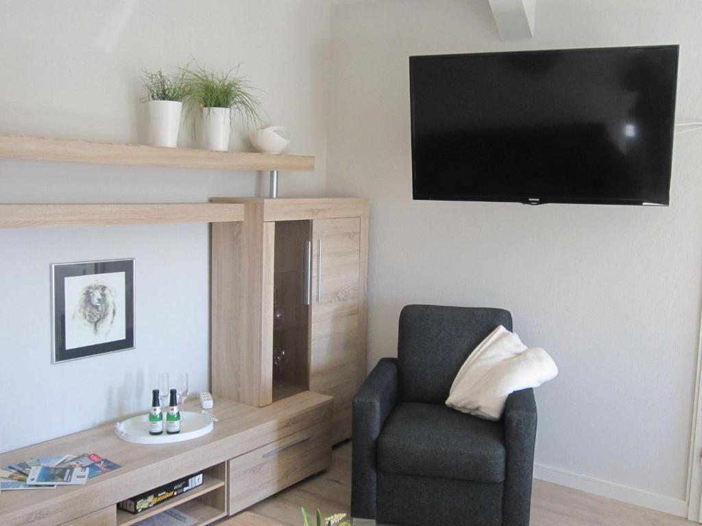 sala de estar con silla y TV de pantalla plana en Ferienwohnung-England, en Nordstrand