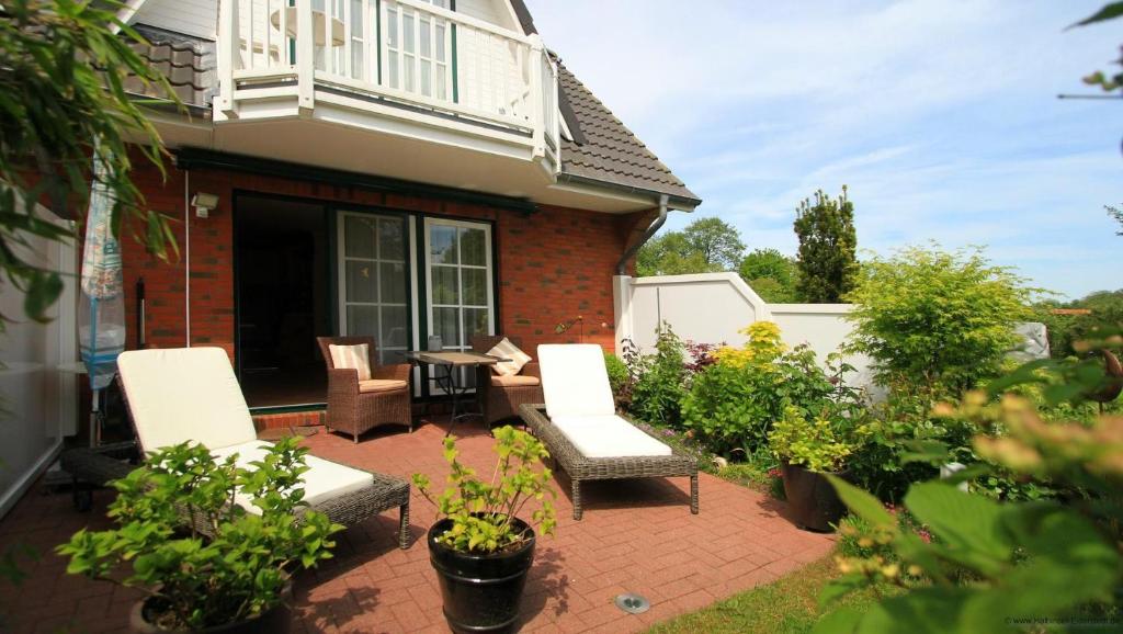 a patio with two chairs and a table in front of a house at Gaestehaeuser-Heidehof-Wohnung-5 in Süderhöft