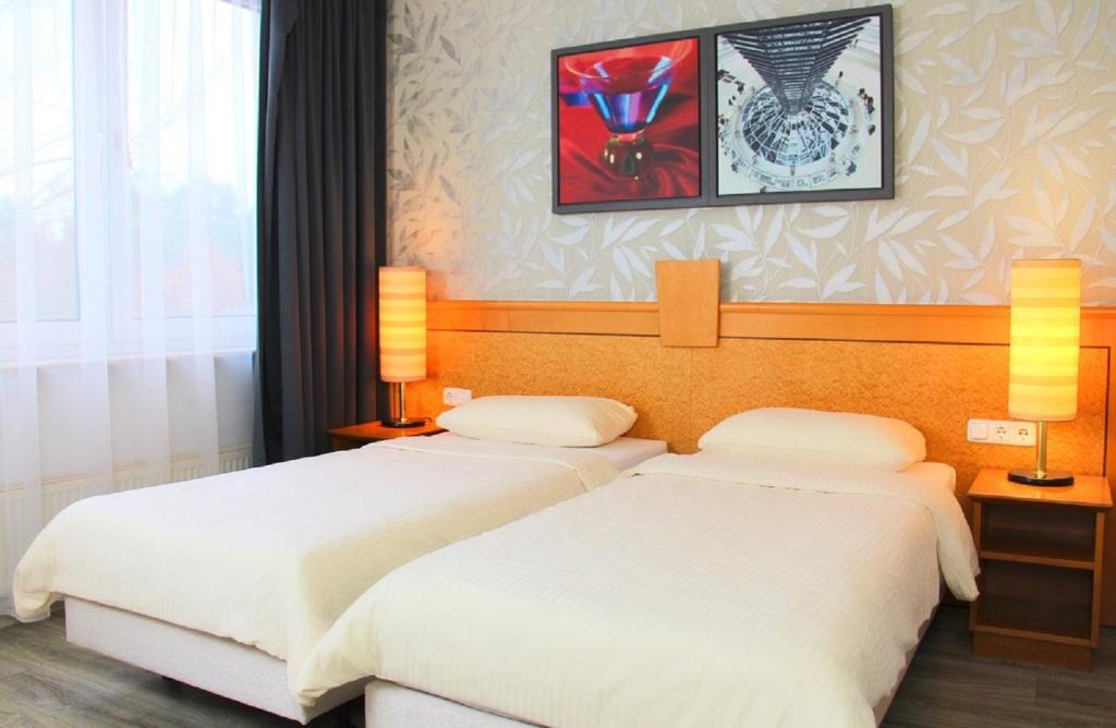 duas camas num quarto de hotel com lençóis brancos em Parkhotel Viktoria em Velten