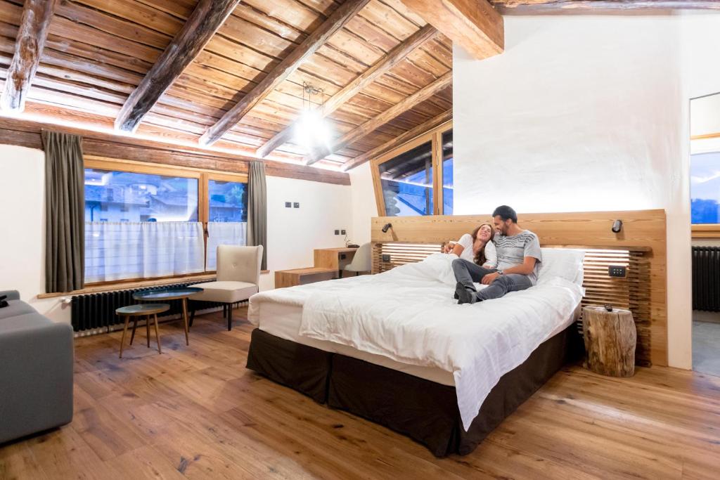 um homem sentado numa cama num quarto em Curt di Clement Eco Mobility Hotel em Tirano
