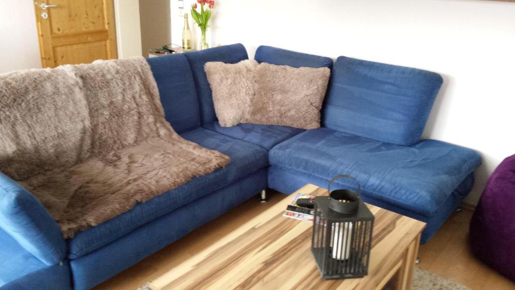 ein blaues Sofa im Wohnzimmer mit Couchtisch in der Unterkunft Ferienwohnung Burgblick in Neuravensburg in Haggen