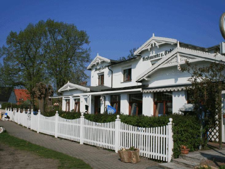 a white house with a white picket fence at Strand-Hotel Lobbe in Lobbe