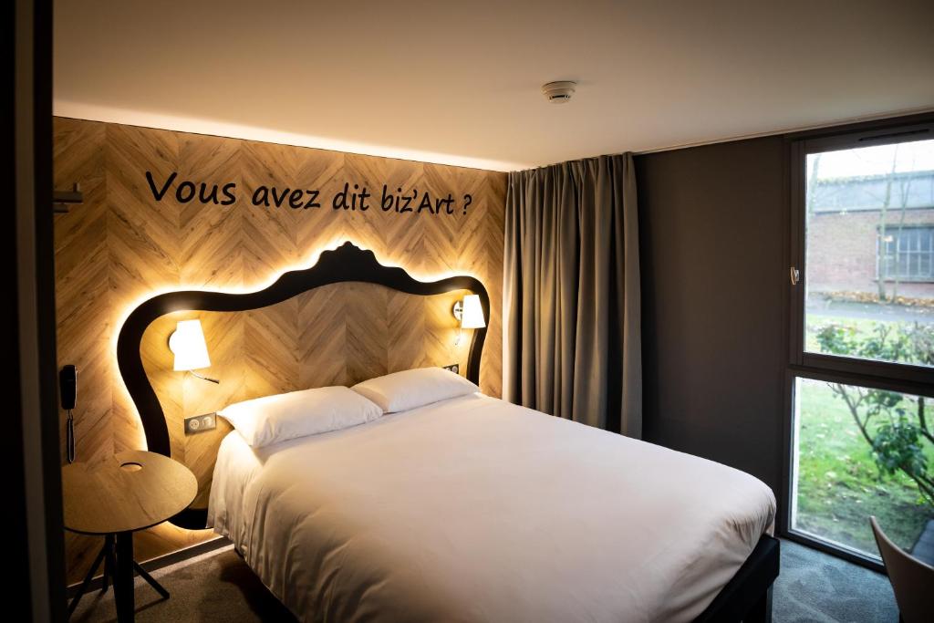 - une chambre avec un lit et un panneau mural dans l'établissement ibis Styles Douai Gare Gayant Expo, à Douai