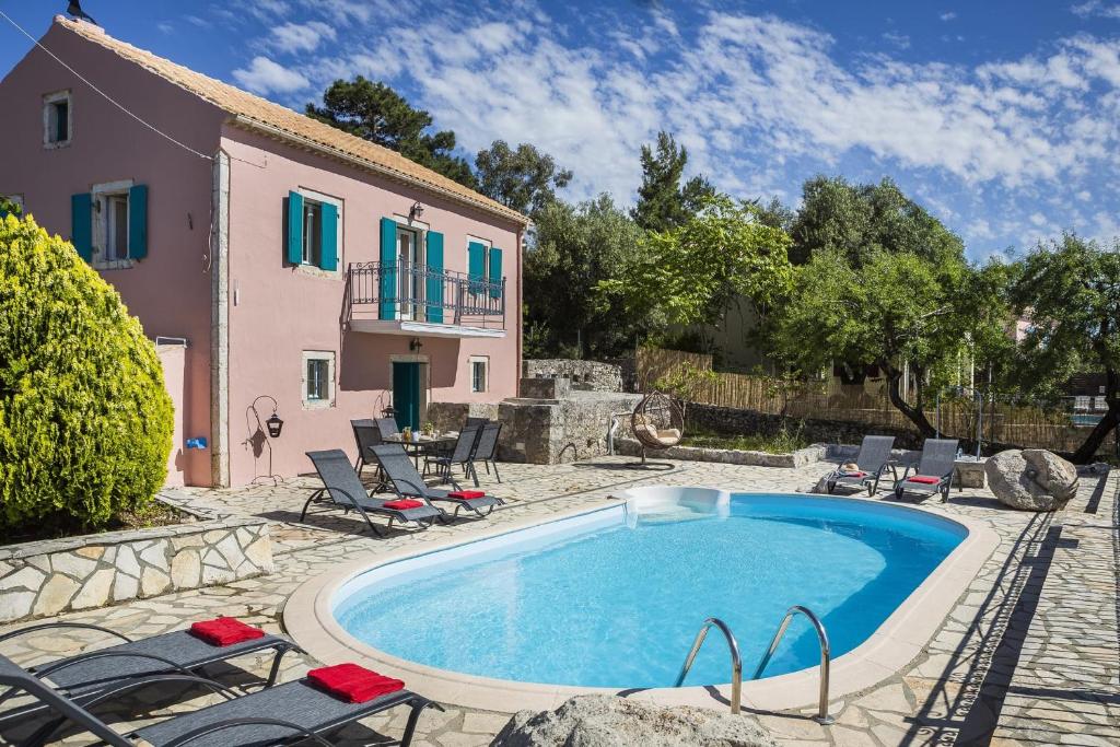 an outdoor swimming pool with chairs and a house at Villa Fantastic View in Khalikerí