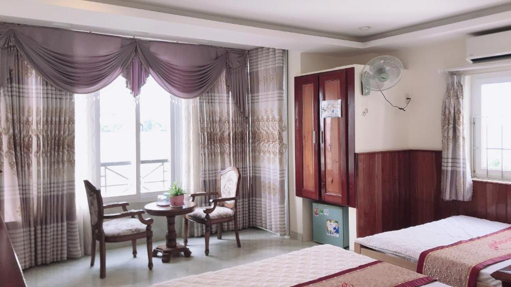 a bedroom with two beds and a table and a window at Hoang Son Hotel in Nha Trang