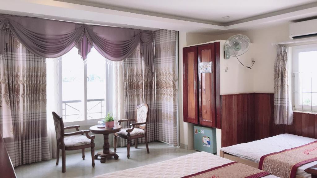 a bedroom with two beds and a table and a window at Hoang Son Hotel in Nha Trang