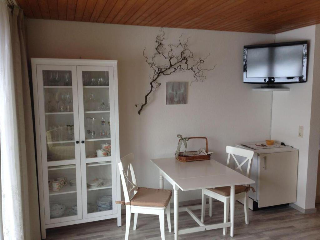 a dining room with a table and a tv on the wall at Schwarzwaldhut in Häusern