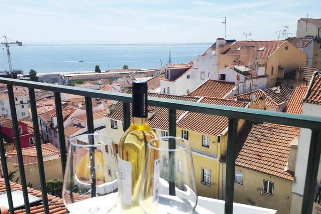 una bottiglia di vino seduta su un balcone con due bicchieri di Alfama Stunning River and Historic City Views 2Bedrooms & 2Bathrooms AC Balcony 18th Century Building a Lisbona