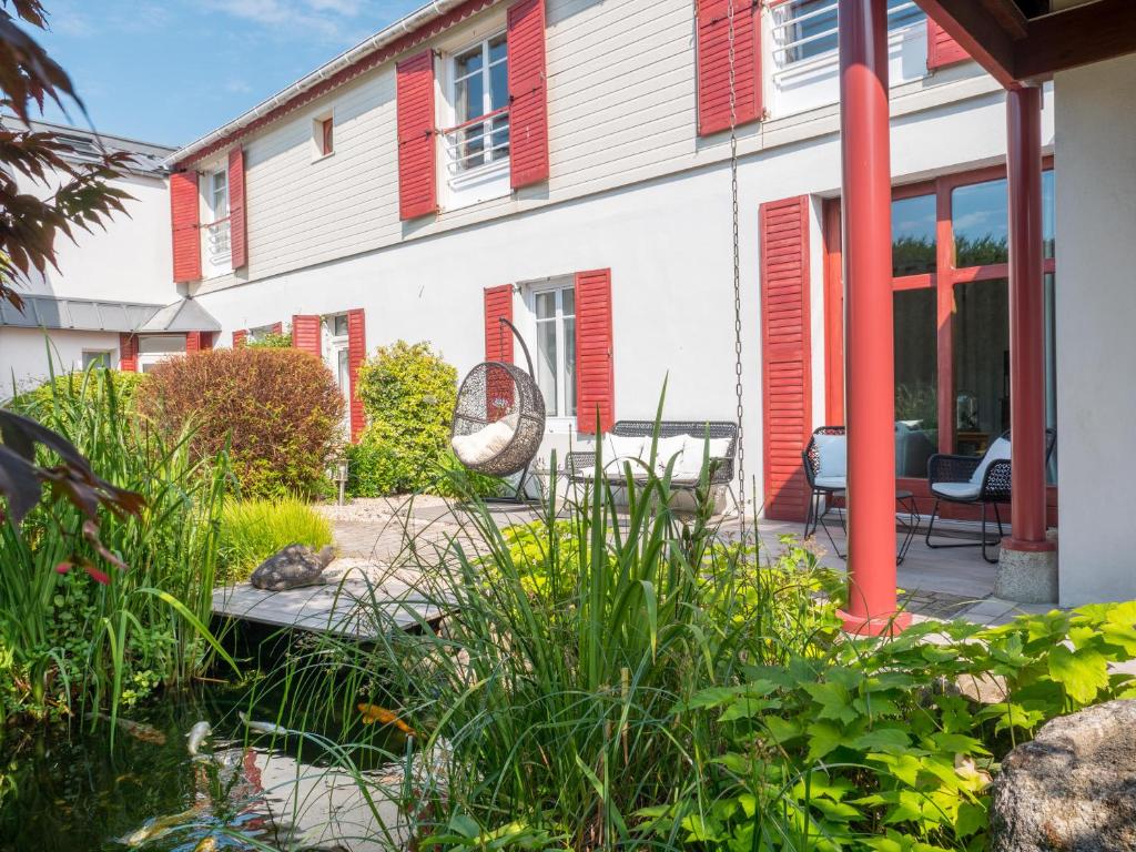 un jardin avec volets rouges en face d'une maison dans l'établissement Villa Kerasy Hotel Spa, à Vannes