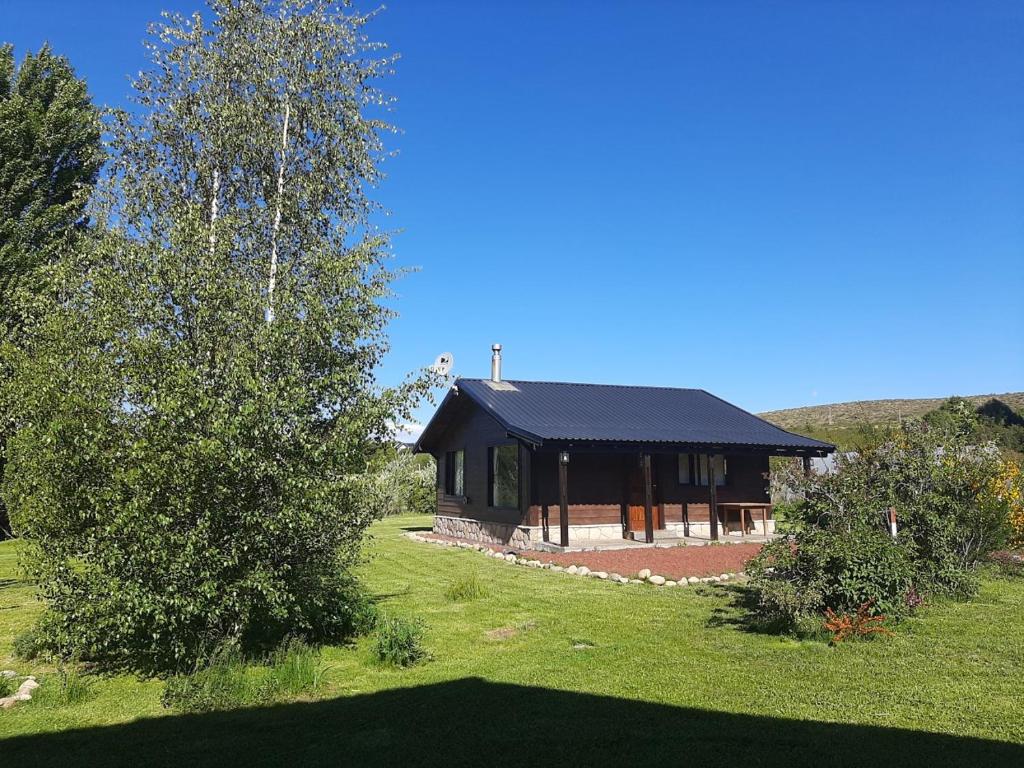 a house with a black roof on a green field at Viento y montaña in San Carlos de Bariloche