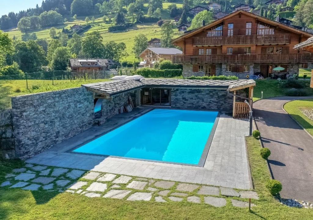 a villa with a swimming pool in front of a house at Résidence Cantarella in Chesières