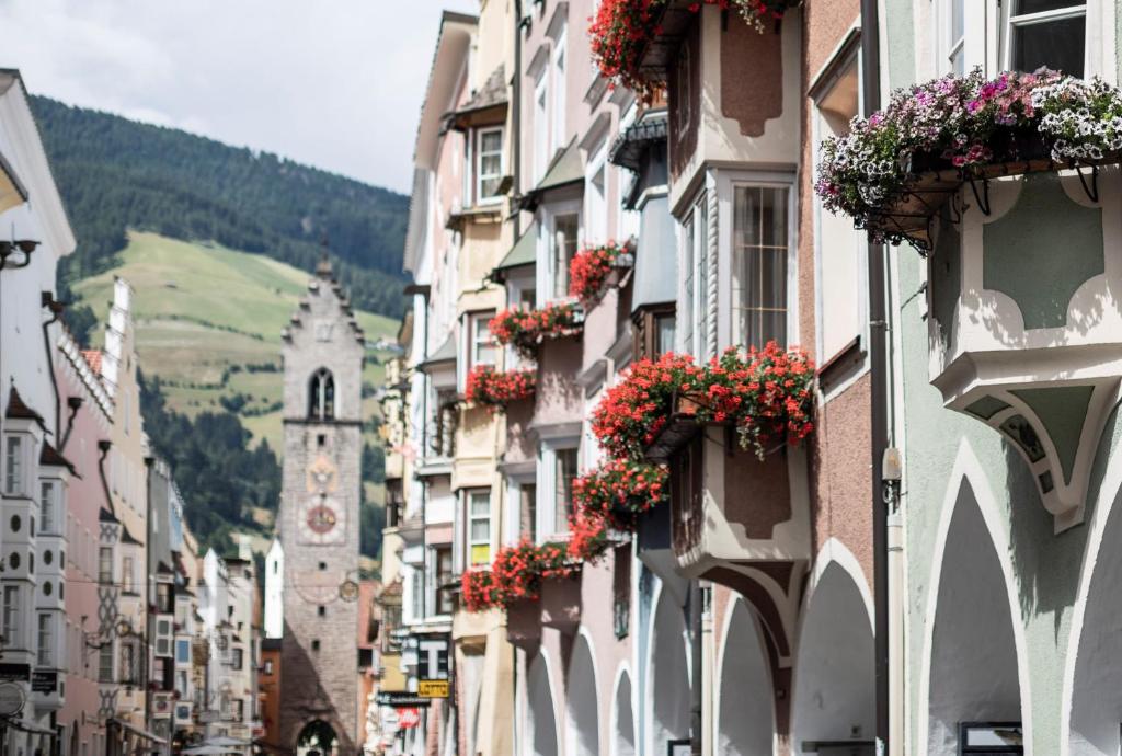 une rue de la ville avec des bâtiments dotés de boîtes de fleurs dans l'établissement Laube35 Central City Apartments, à Vipiteno