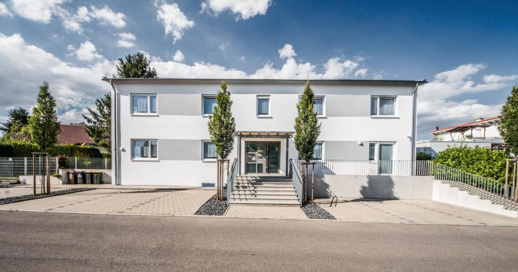 une maison blanche avec des arbres devant elle dans l'établissement Apartment Lichtenwald, à Thomashardt