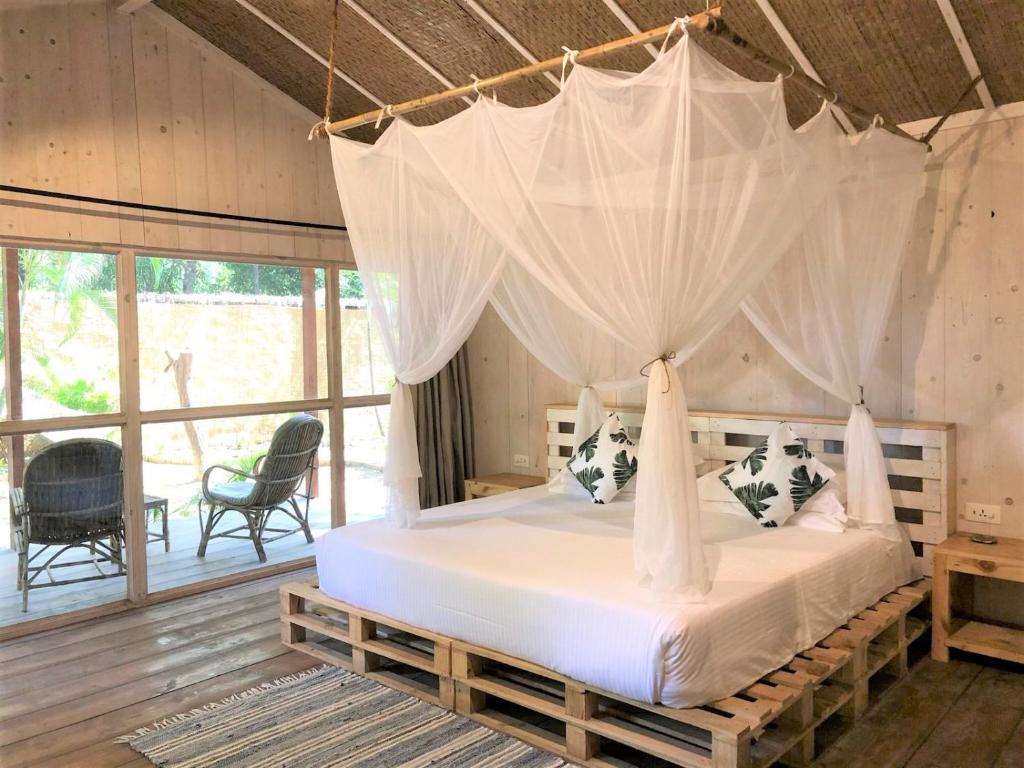 a bedroom with a bed with a mosquito net at Palm Forest Palolem in Palolem