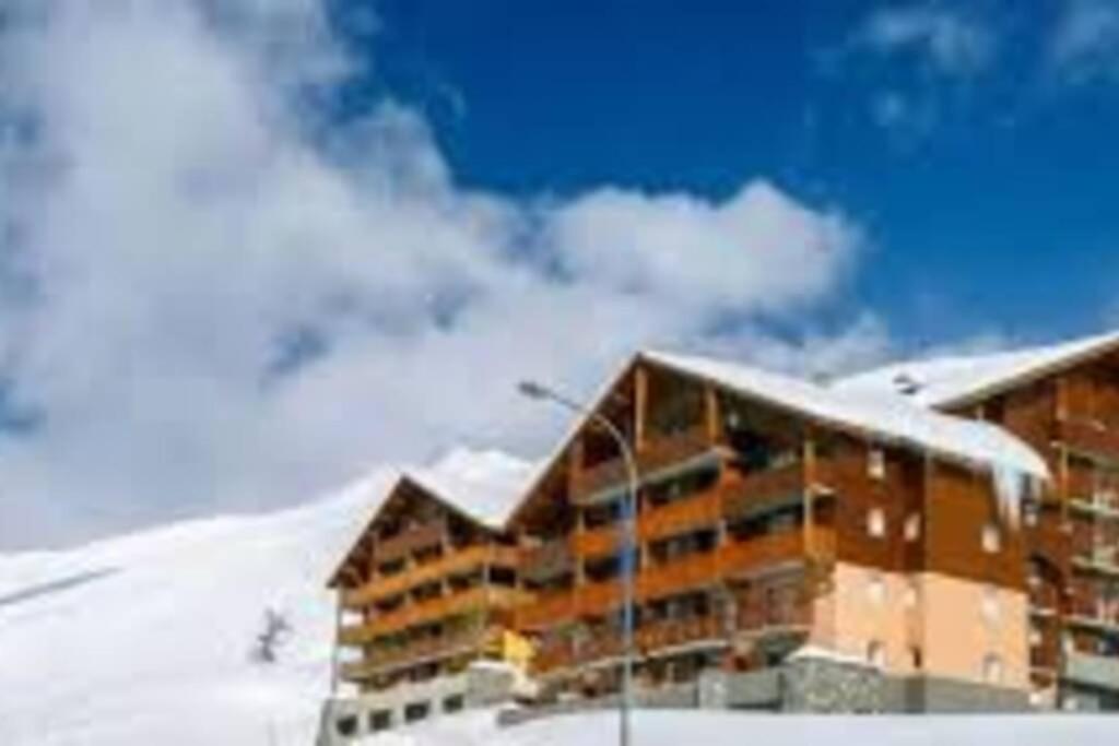 un edificio con nieve en el suelo junto a una montaña en Superbe appartement la Foux d'Allos en La Foux