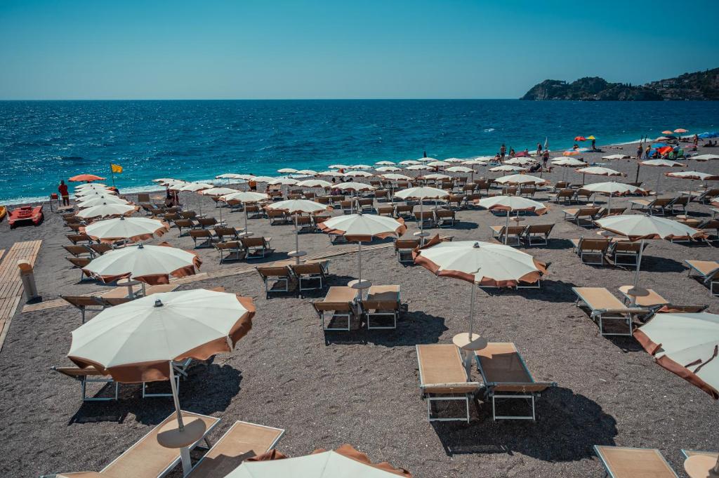 a bunch of chairs and umbrellas on a beach at Hotel Rivage Taormina in Taormina