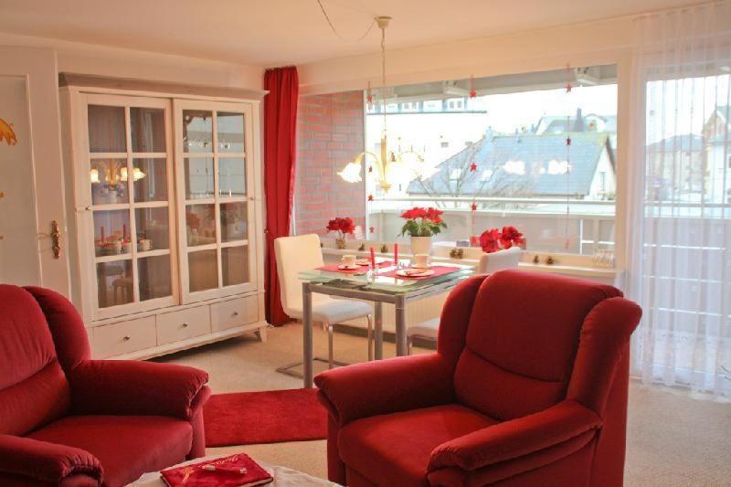 a living room with red chairs and a table and a dining room at Nordsee-Residenz-City-App-18 in Westerland