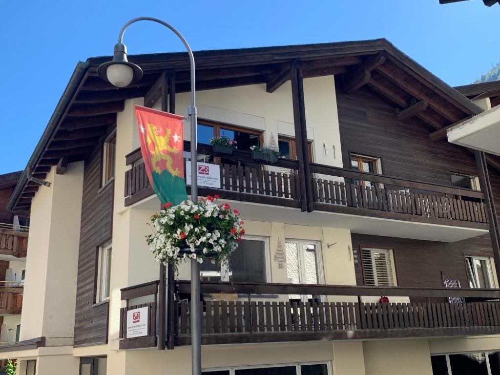 - un bâtiment avec un balcon drapeau et des fleurs dans l'établissement Central & Elegant Apartments,partially with Fireplace, by Zermatt Rental, à Zermatt