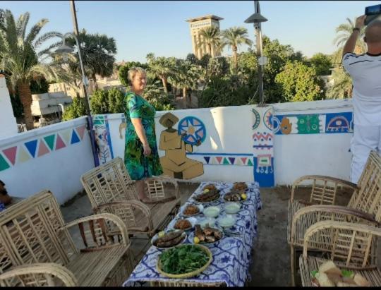 a woman standing next to a table with plates of food at Roma House in Aswan