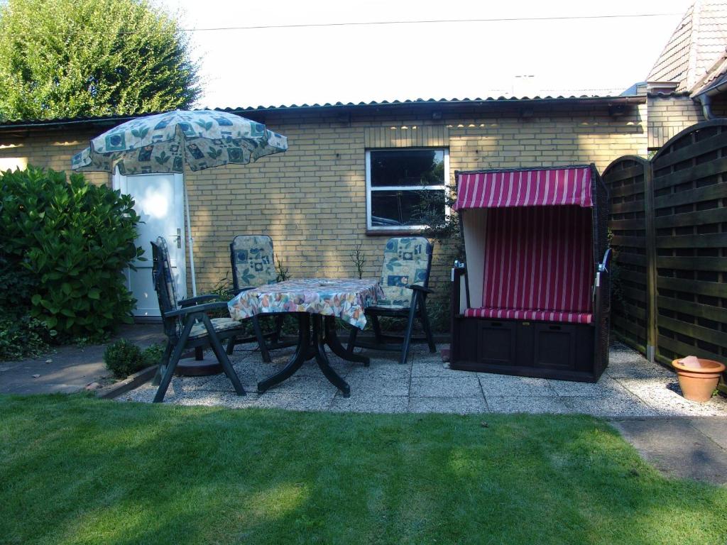 a patio with a table and chairs and an umbrella at Andrea-OG in Büsum