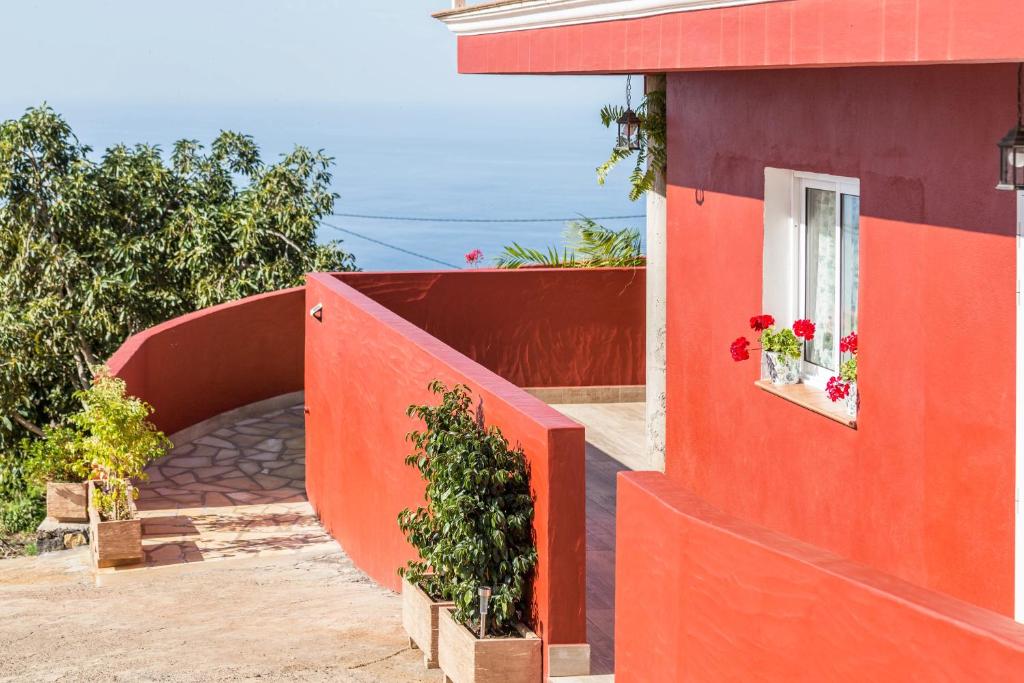 ein rotes Gebäude mit Blumen im Fenster in der Unterkunft Casa Quintana - Apartamento Carla in Tijarafe