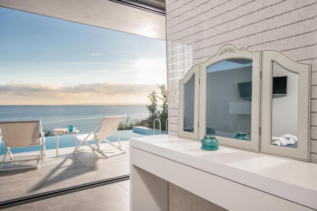 a bathroom with a mirror and a view of the ocean at Zante Fiore Suites in Xirokástellon