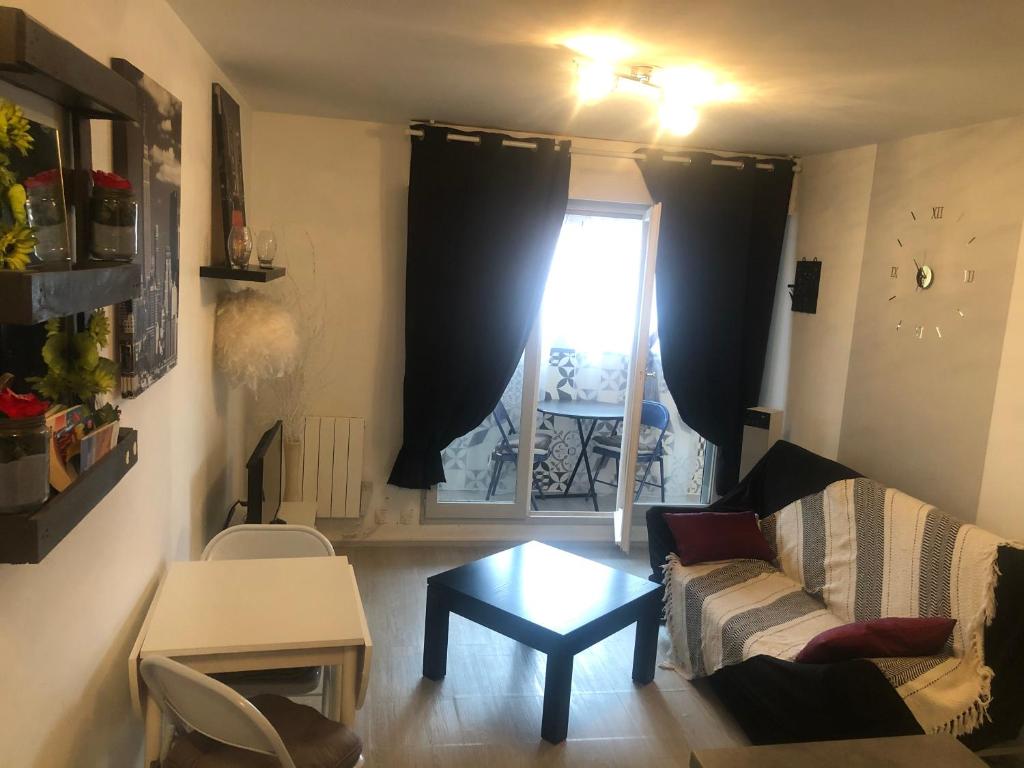 - un salon avec un canapé, une table et une fenêtre dans l'établissement Avenue des Gabions résidence super deauville, à Villers-sur-Mer