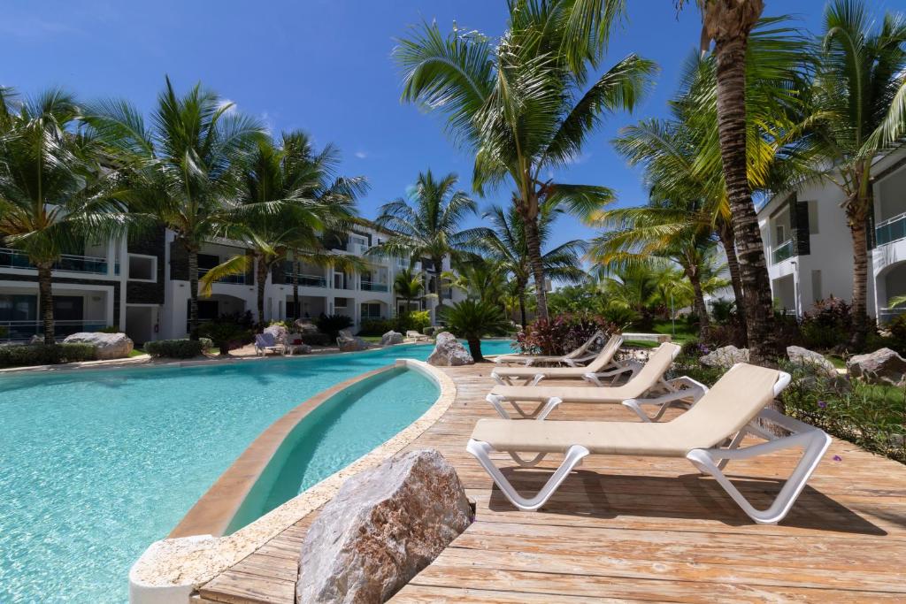 a resort pool with lounge chairs and palm trees at Atmospheric apartment with a beautiful view of the swimming pool in Bayahibe