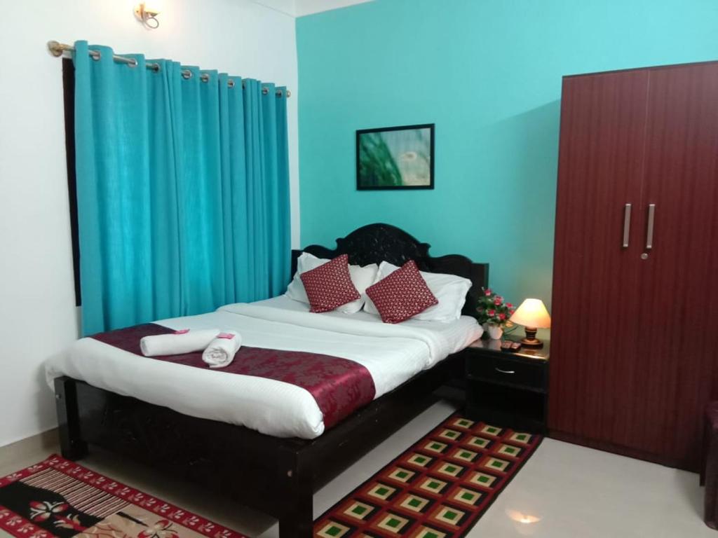 a bedroom with a large bed with blue walls at Coorg Homeland Homestay -With Kitchenette in Madikeri