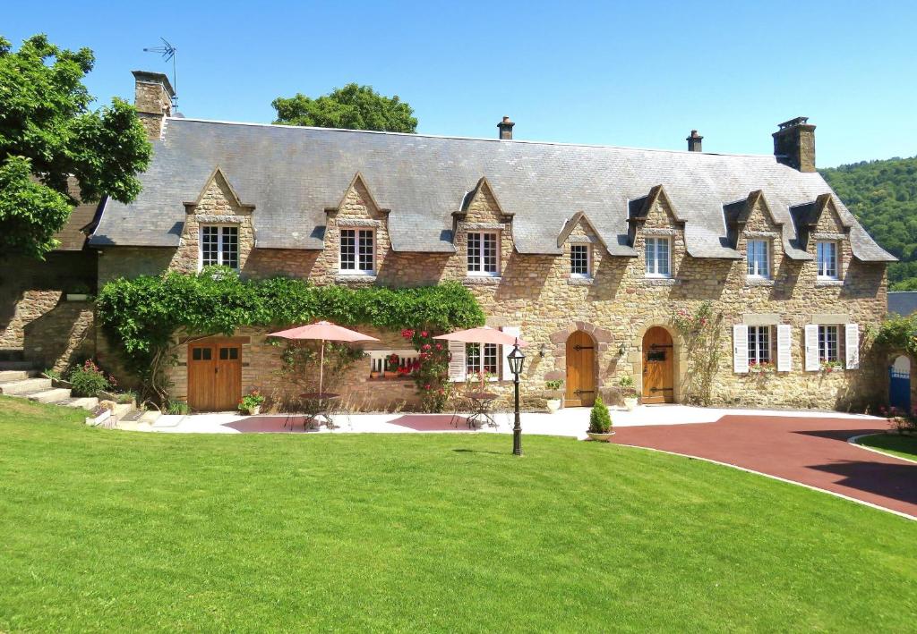 uma grande casa de pedra com um relvado verde em Le Manoir de Placy - Chambres d'Hôtes em Clécy