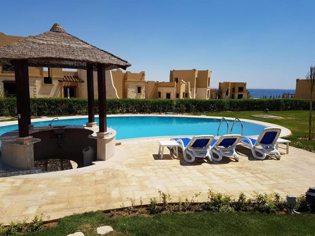 un grupo de sillas sentadas junto a una piscina en Byoum Vacation House, en El Fayum