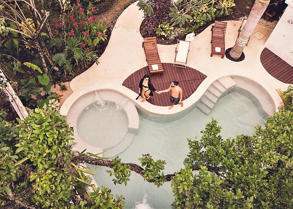 an overhead view of two people standing next to a swimming pool at Hotel Aires Bacalar in Bacalar