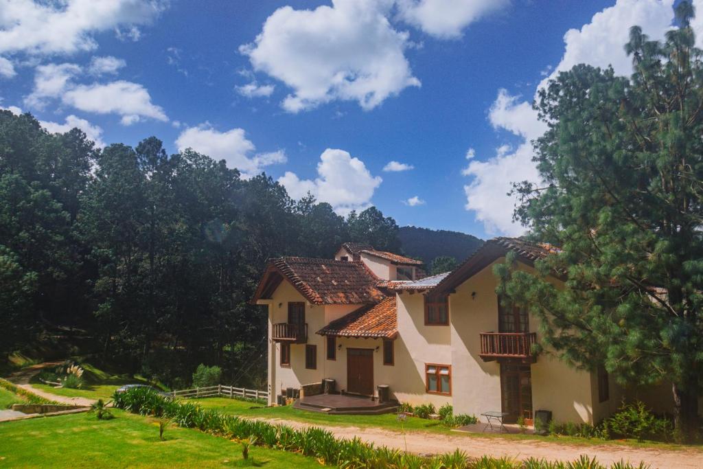 a house in a field with trees in the background at CORTIJO LA CASONA & Bungalow al Pie de la Montaña in San Cristóbal de Las Casas