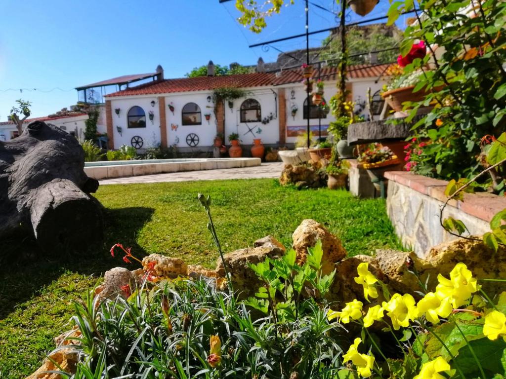 un jardin avec des fleurs jaunes devant une maison dans l'établissement Casa Proyecto Pepe Bravo - Arte de manos y corazón, à Alozaina