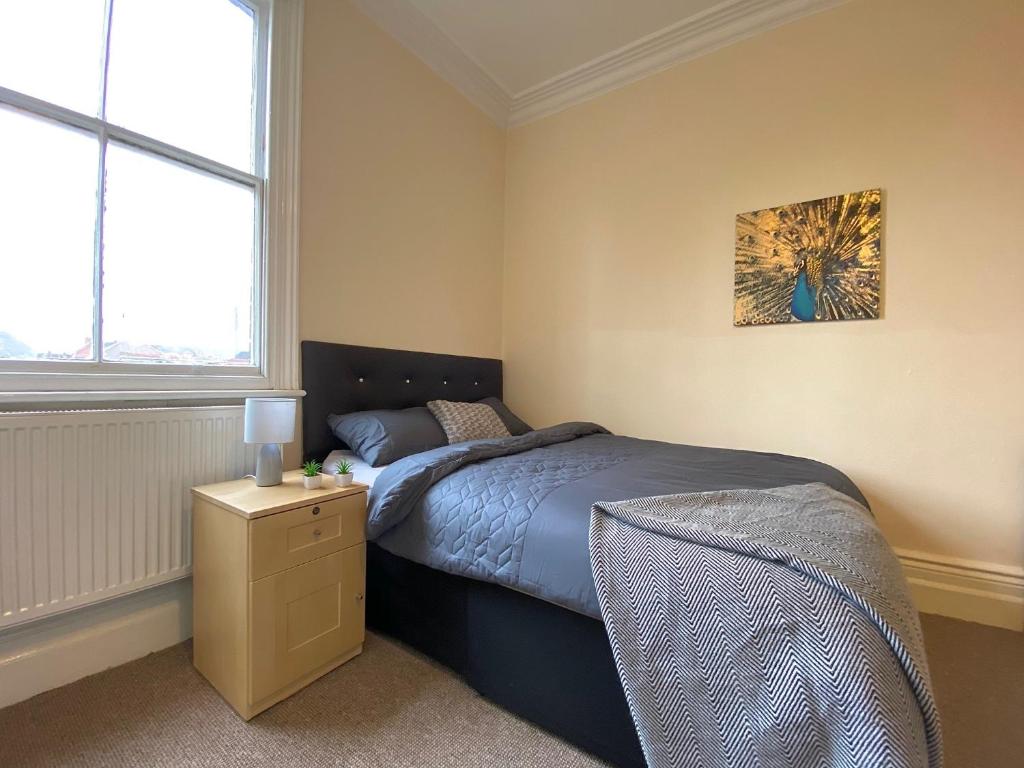 a bedroom with a bed and a lamp on a night stand at Spacious Victorian Studio Flat in Doncaster