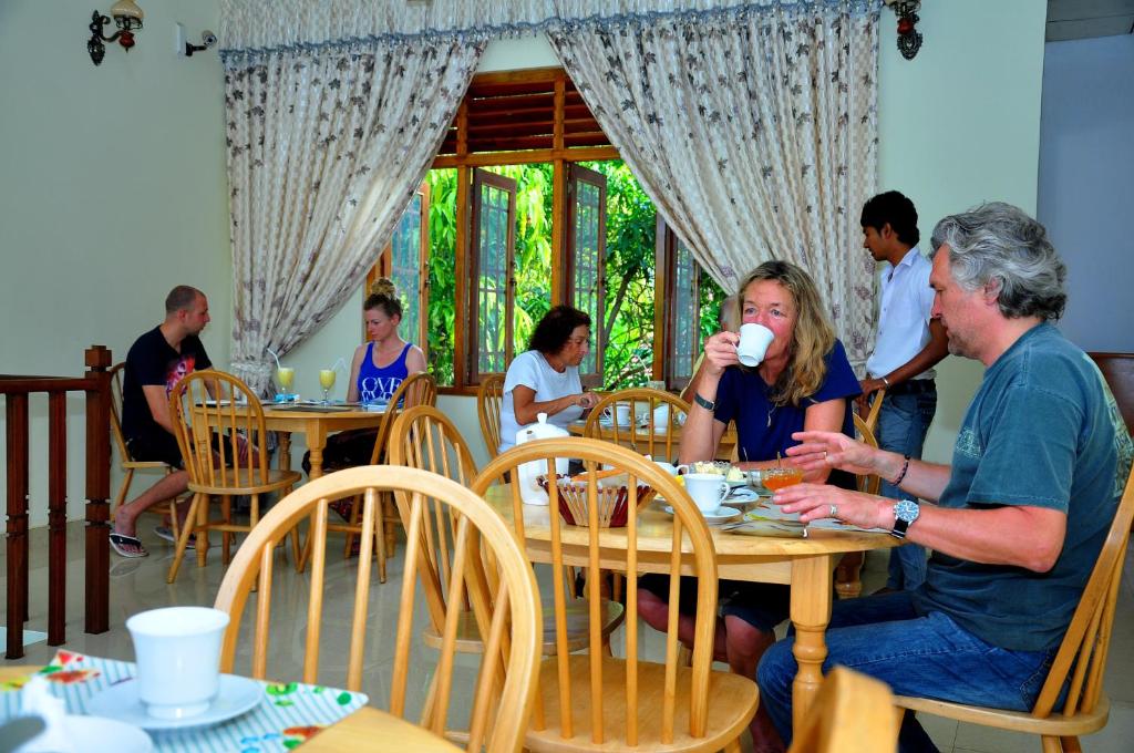 un hombre y una mujer sentados en una mesa bebiendo café en London Palace, en Anuradhapura