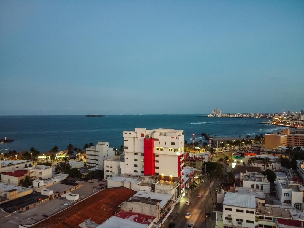 una città con un edificio rosso di fronte all'oceano di Hotel Ziami a Veracruz
