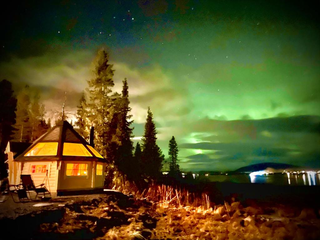 a cabin on the shore of a lake at night at Northern Light Camp in Kiruna