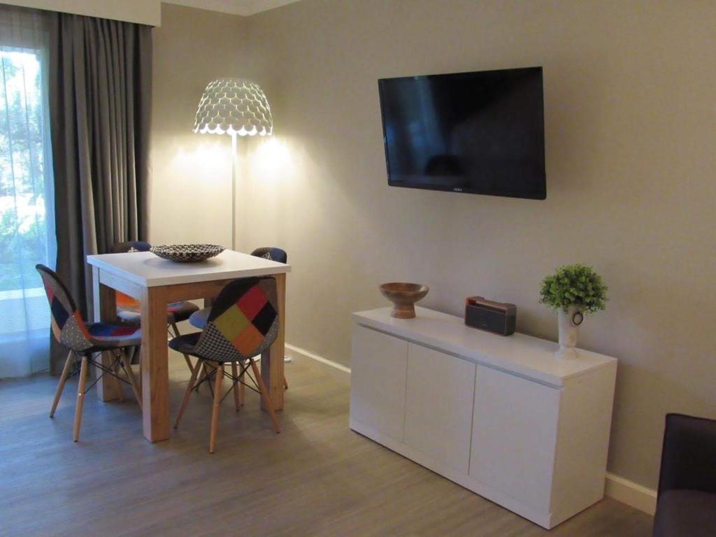 a living room with a table and a tv on the wall at Forest Lagoon Apartamento 6 in Punta del Este