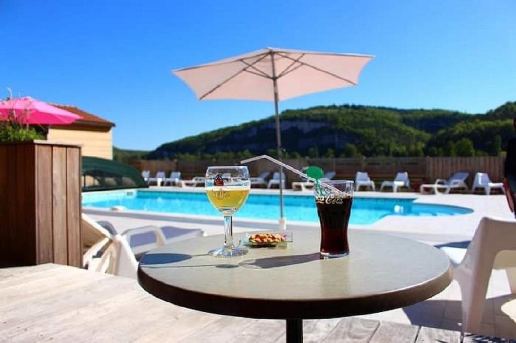 a table with two glasses of wine and an umbrella at Hôtel Les Gabarres in Tour-de-Faure